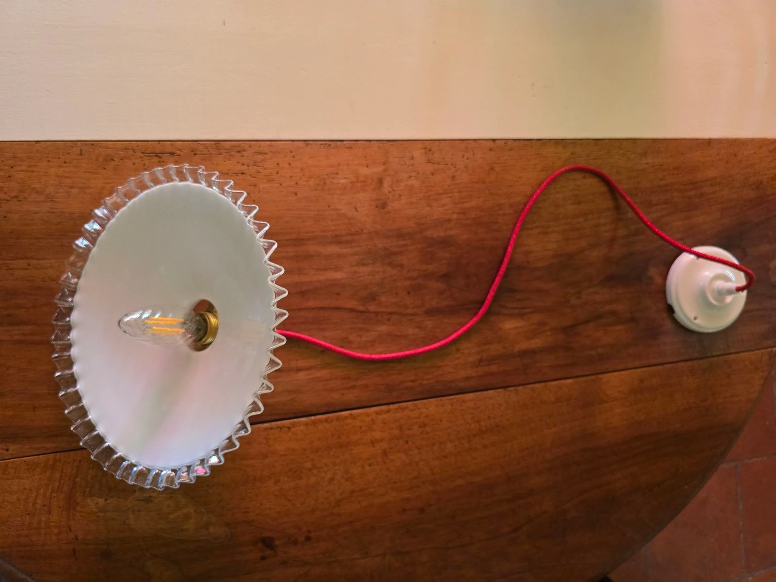 Lámpara de techo con disco opalino blanco y bordes transparentes sobre cable rojo y plafón de porcelana – photo 5